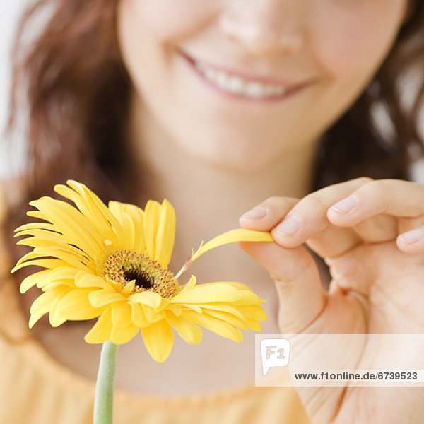 Teenage girl plucking flower petal