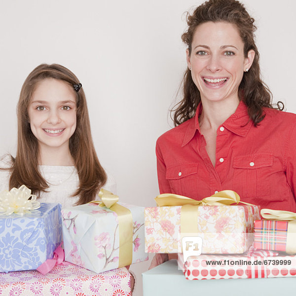 Mother and daughter (10-12 years) with stack of presents  smiling  portrait
