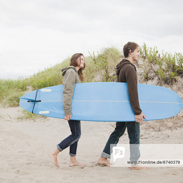 Couple carrying surfboard
