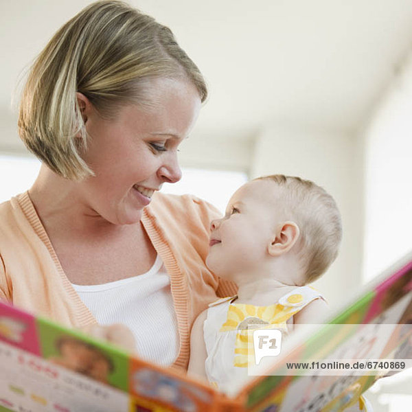 Mother reading book to her baby daughter
