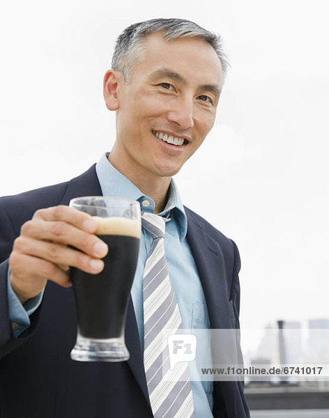 Businessman holding pint of ale and looking at camera