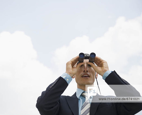 Businessman looking away through binoculars