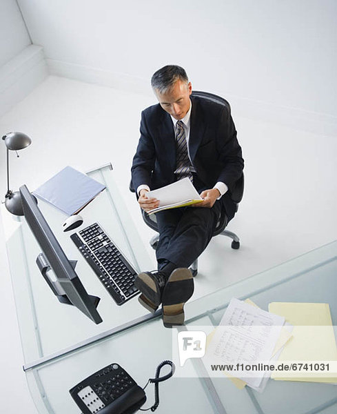 Businessman reading documents in office with feet on desk