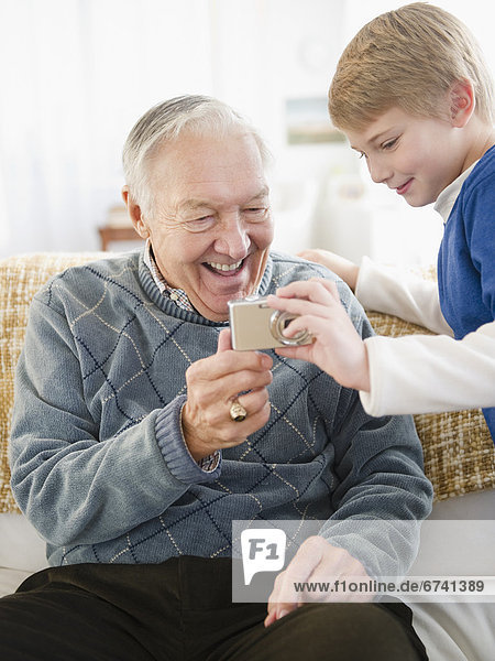Grandfather and grandson (8-9) holding digital camera