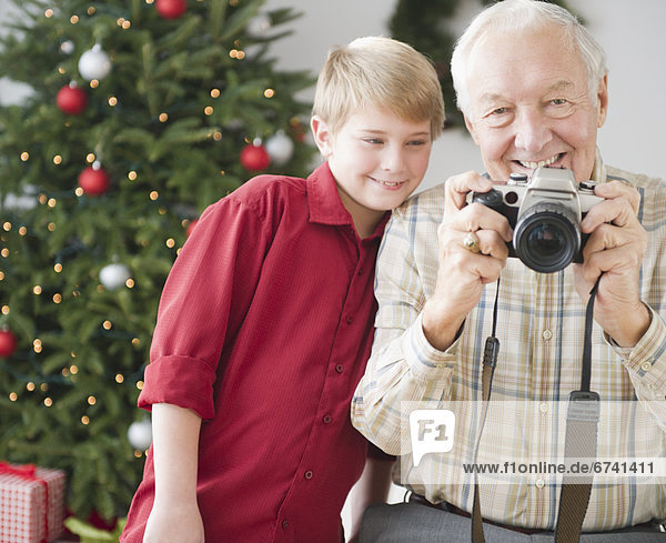 Grandfather and grandson (8-9 years) taking picture  christmas tree in background