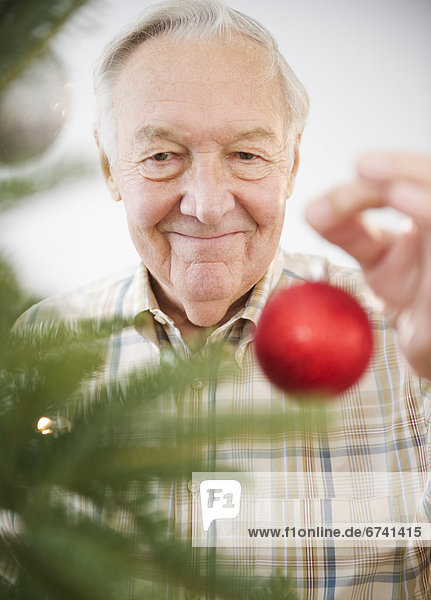 Senior Senioren Portrait Mann Weihnachtsbaum Tannenbaum schmücken