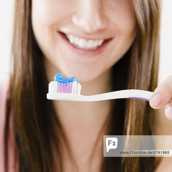 Close-up of smiling young woman holding toothbrush