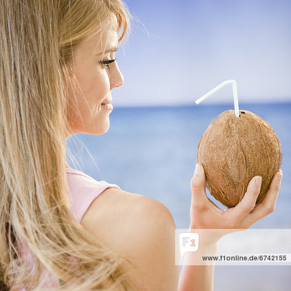 Profile of woman holding coconut with straw