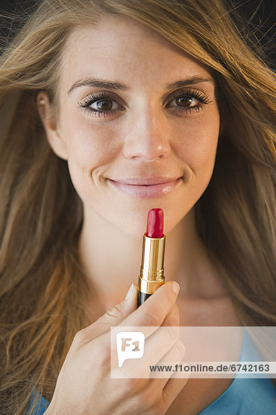 Portrait of woman holding lipstick