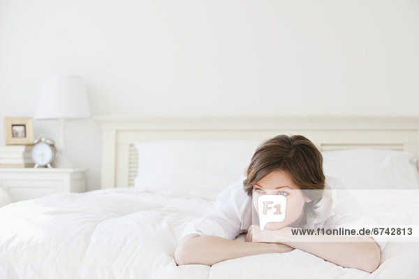 Pensive woman relaxing on bed