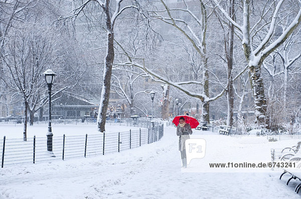 Woman walking with red umbrella on a snowy day