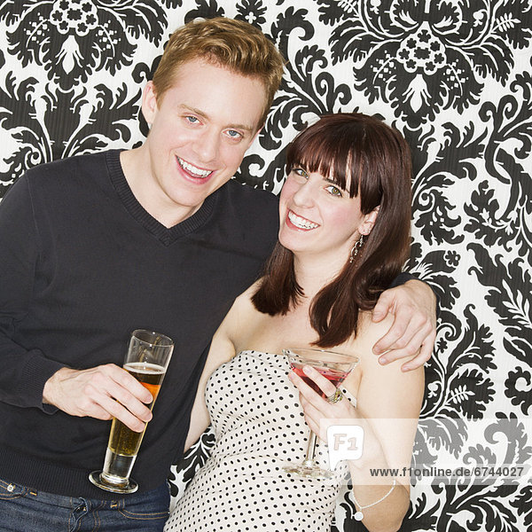Studio portrait of young couple holding drinks