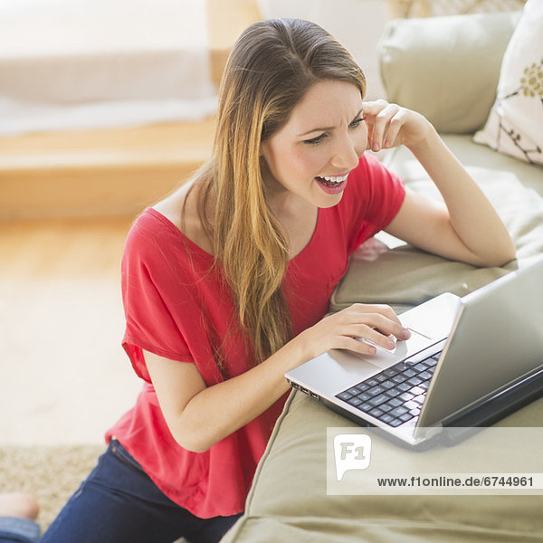 Portrait of young woman working with laptop in living room