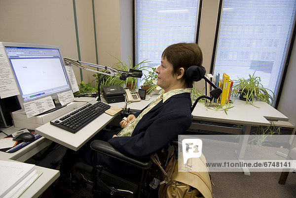 Woman in Wheelchair at Desk using Voice and Touch Pad Controlled Computer in Office  Toronto  Ontario