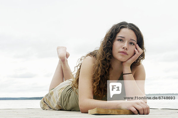 Teen Laying on Dock with a Book
