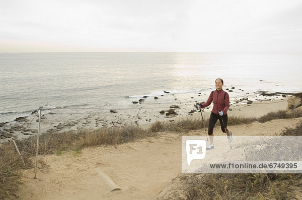 Hispanic woman pole walking along coast in California  United States