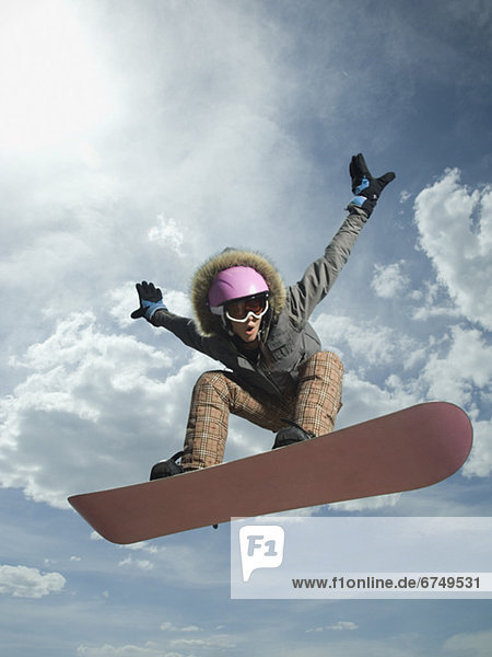 Low angle view of snowboarder jumping