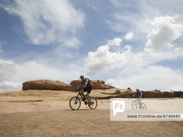 Couple riding mountain bikes in desert