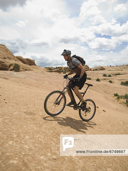 Man riding mountain bike on rock formation
