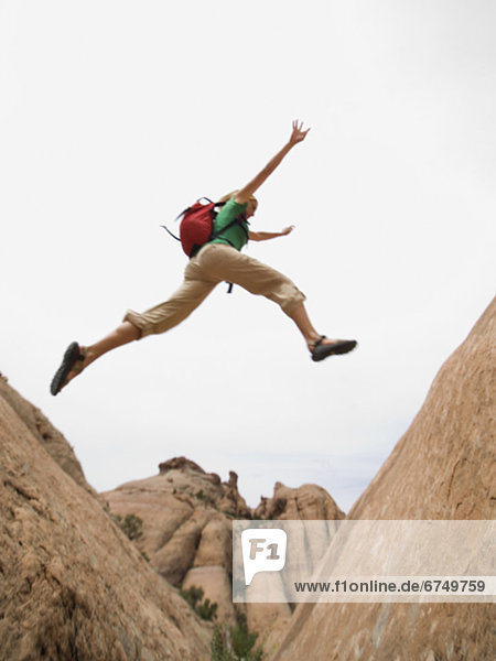 Woman jumping over rock formation