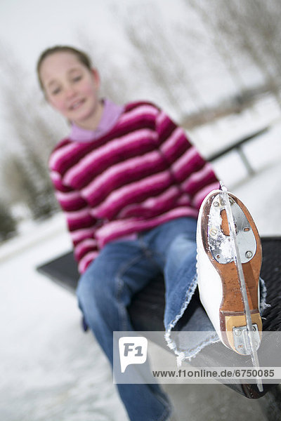 Girl on Bench with Skate Up at Outdoor Ice Rink