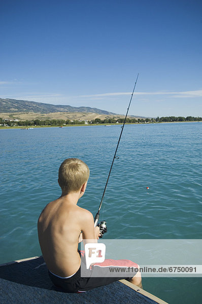 Boy fishing off dock in lake  Utah  United States
