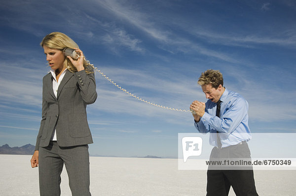 Businesspeople talking with can and string phone  Salt Flats  Utah  United States