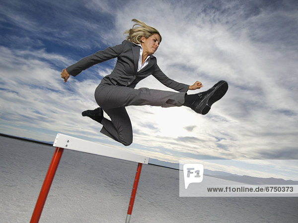 Businesswoman jumping over hurdle  Salt Flats  Utah  United States