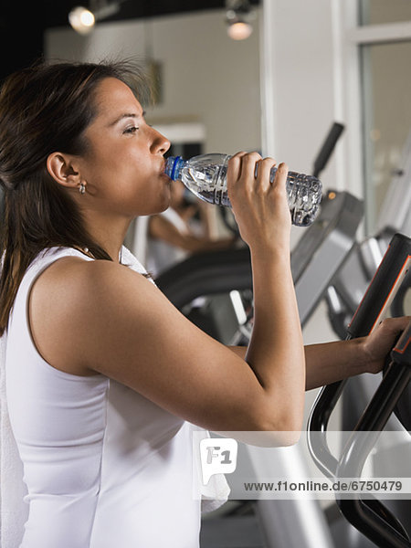 Woman drinking water on exercise machine
