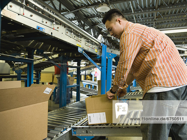 Asian male factory worker checking product