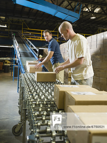 Warehouse workers checking packages on conveyor belt