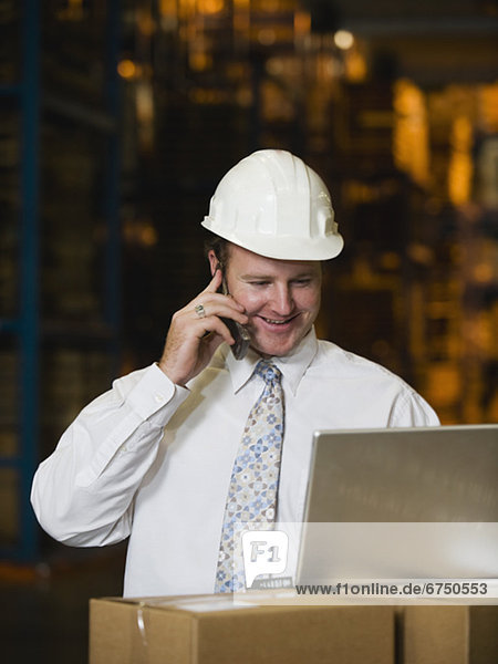 Businessman talking on cell phone in warehouse