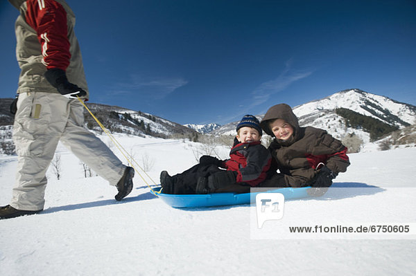 Father pulling children on sled