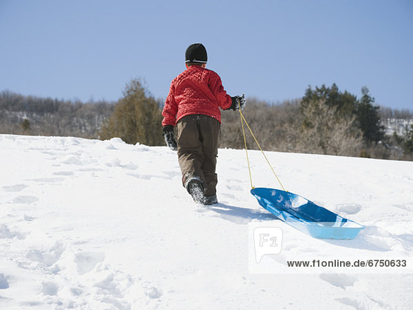 Boy pulling sled in snow