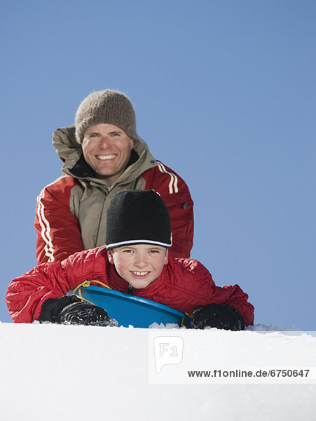 Father and son on sled in snow