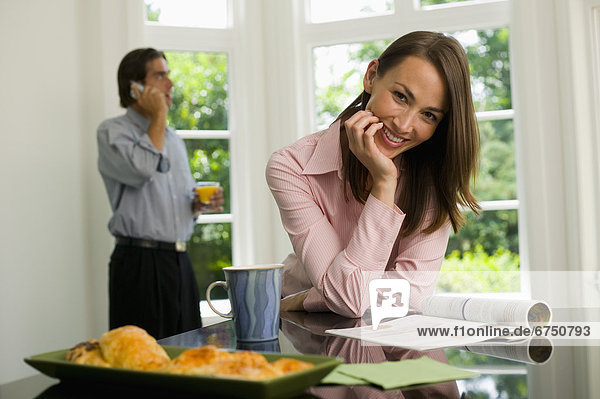 Woman with Magazine  Man on Cellphone in Kitchen