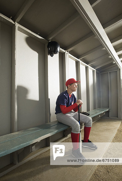 Serious baseball player sitting in dugout