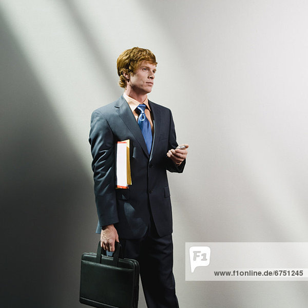Businessman holding cell phone  files and briefcase