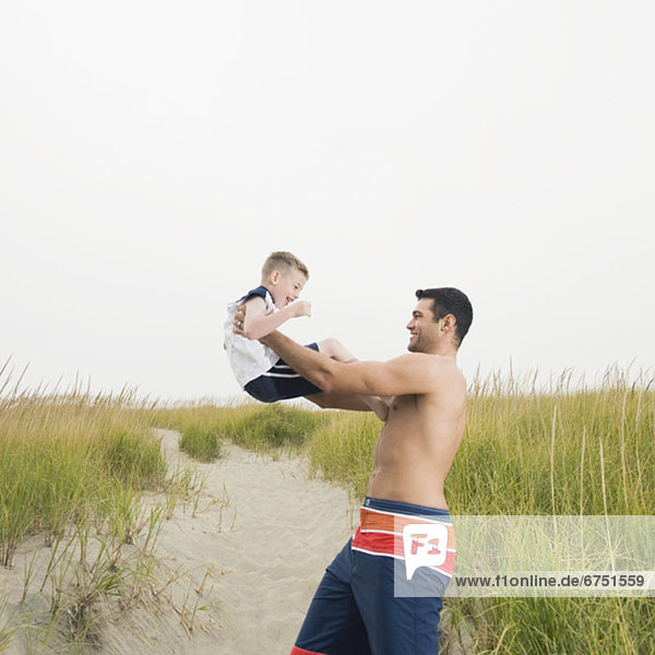 Father lifting son on beach