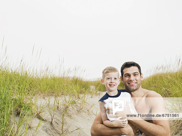 Portrait of father and son hugging on beach