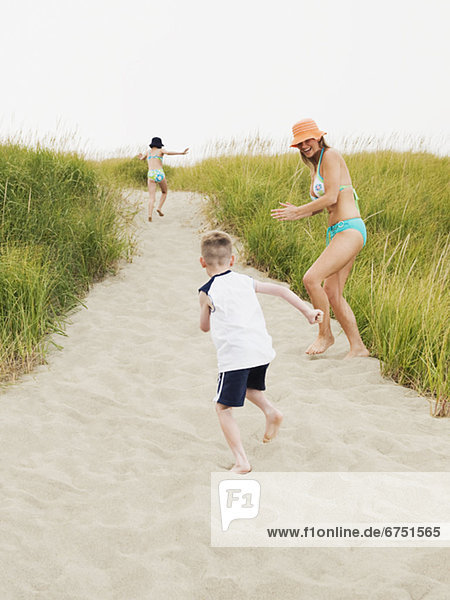 Mother running on beach with daughter and son