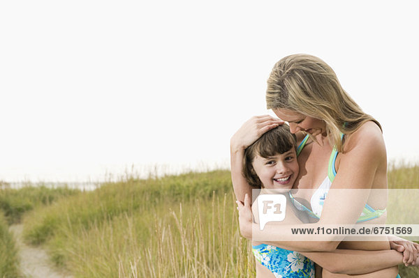 Portrait of mother hugging daughter on beach