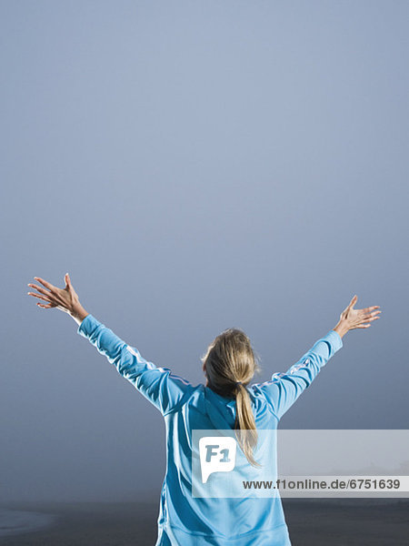Woman with arms outstretched on foggy beach