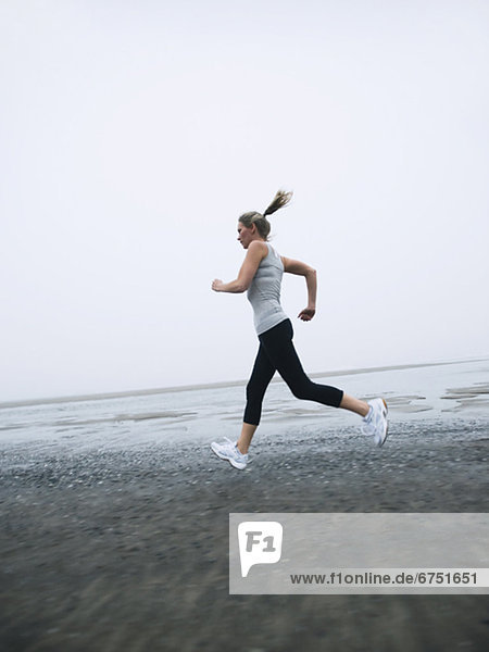 Woman jogging on foggy beach