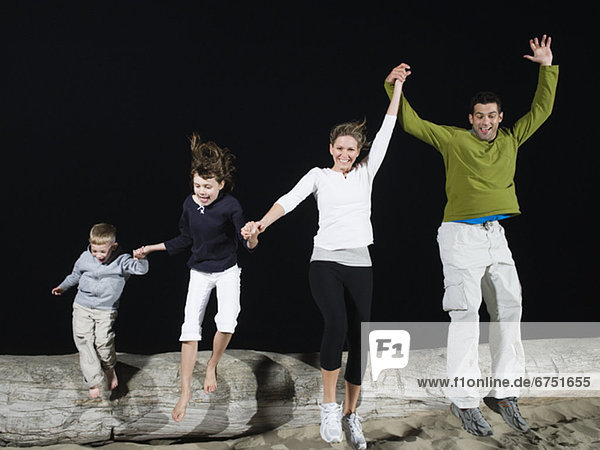 Family jumping off driftwood