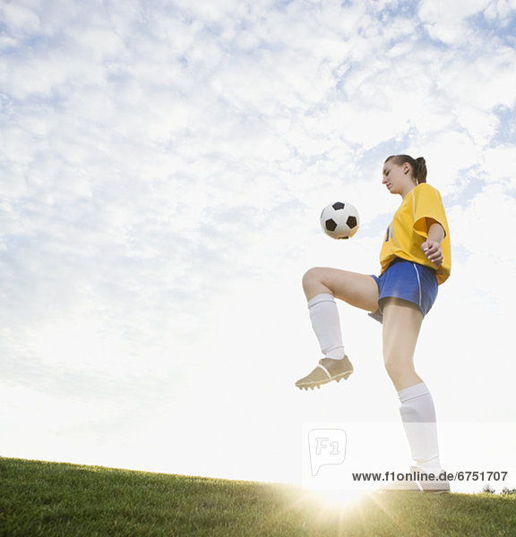 Teenage girl bouncing soccer ball on knee
