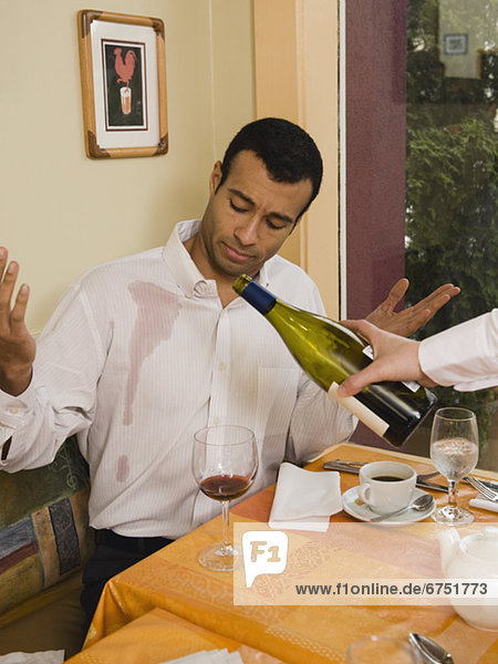 Waiter spilling wine on customer