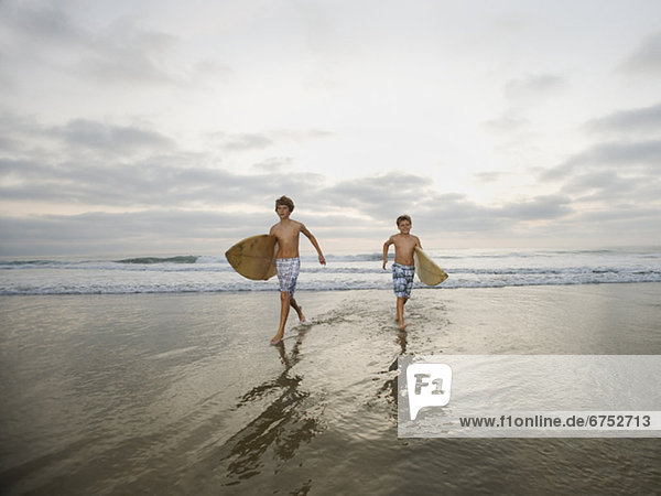 Boys running with surfboards