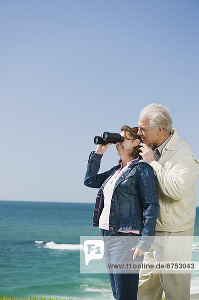 Couple looking at ocean with binoculars