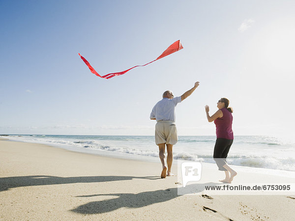 Couple flying kite on beach